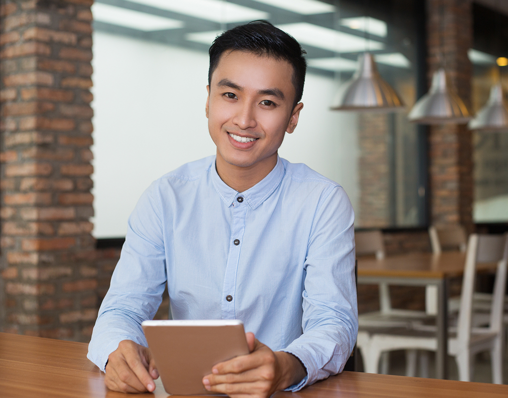 Smiling man working on a tablet at a cafe table — offshore professional